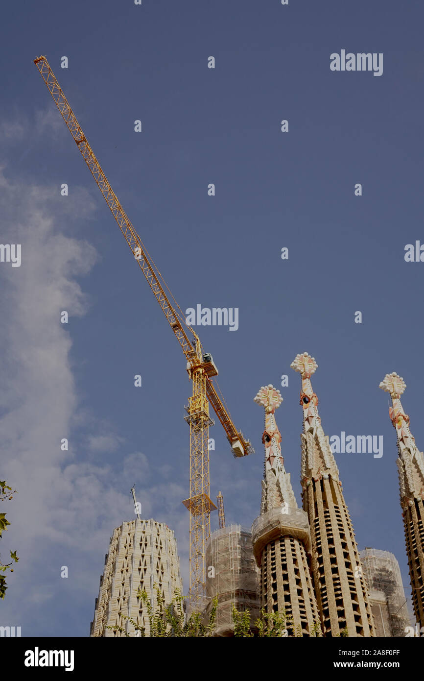 The spires of Sagrada Familia Basilica next to a yellow crane Stock Photo