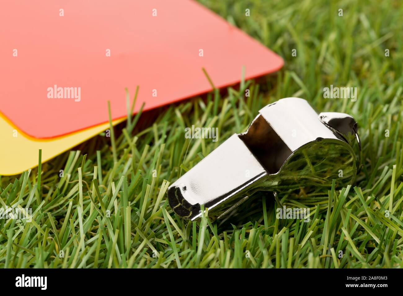 Soccer sports referee yellow and red cards with chrome whistle on grass background - penalty, foul or sports concept, selective focus Stock Photo