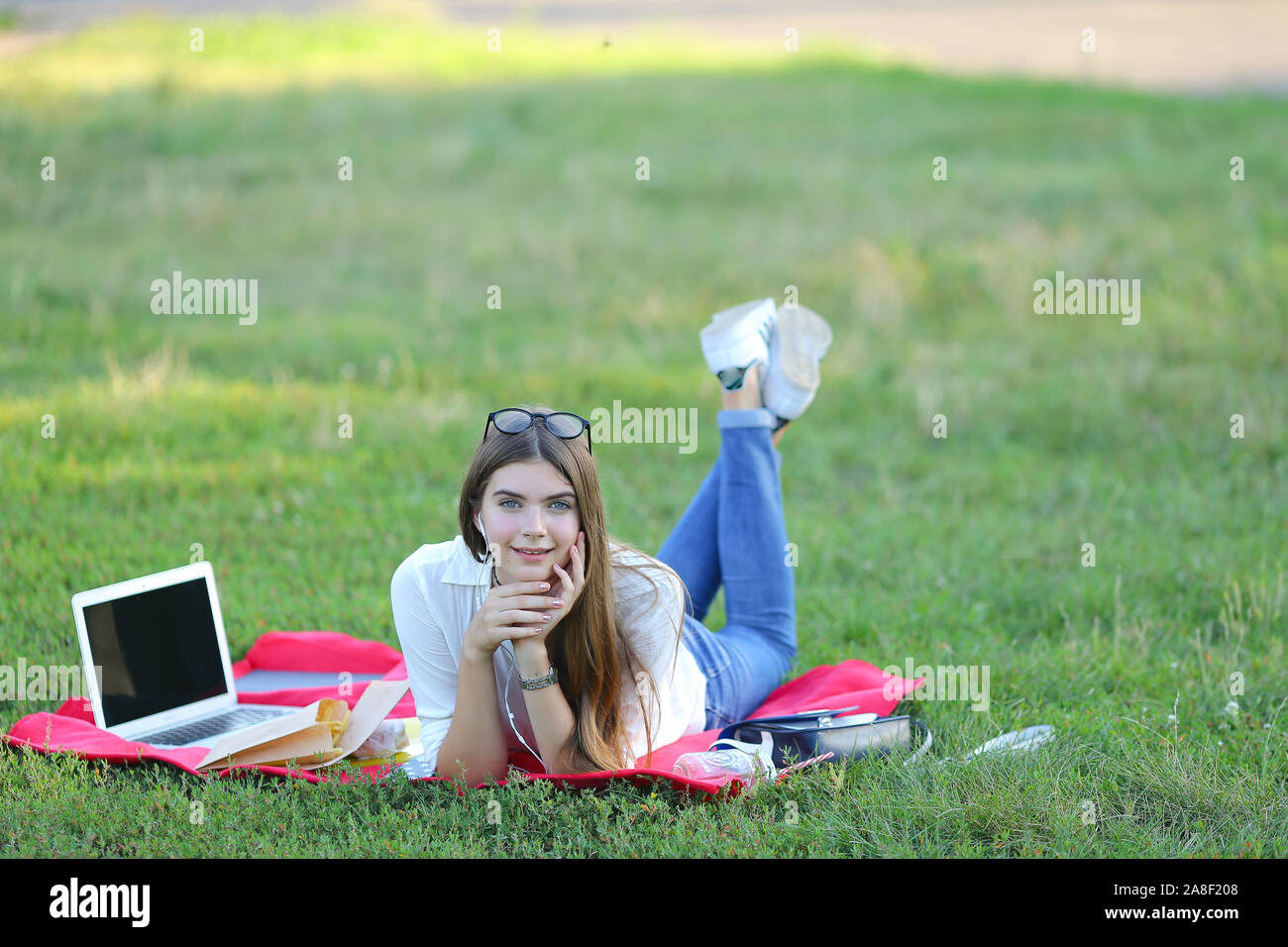 young girl lying on the grass in the park and works at a laptop Stock ...