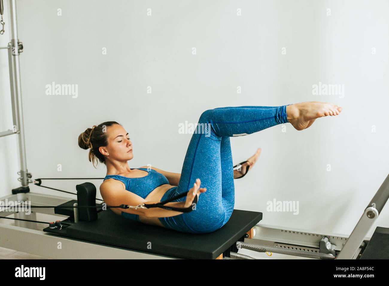 Woman performing Pilates exercise using a Cadillac or Trapeze table Stock Photo