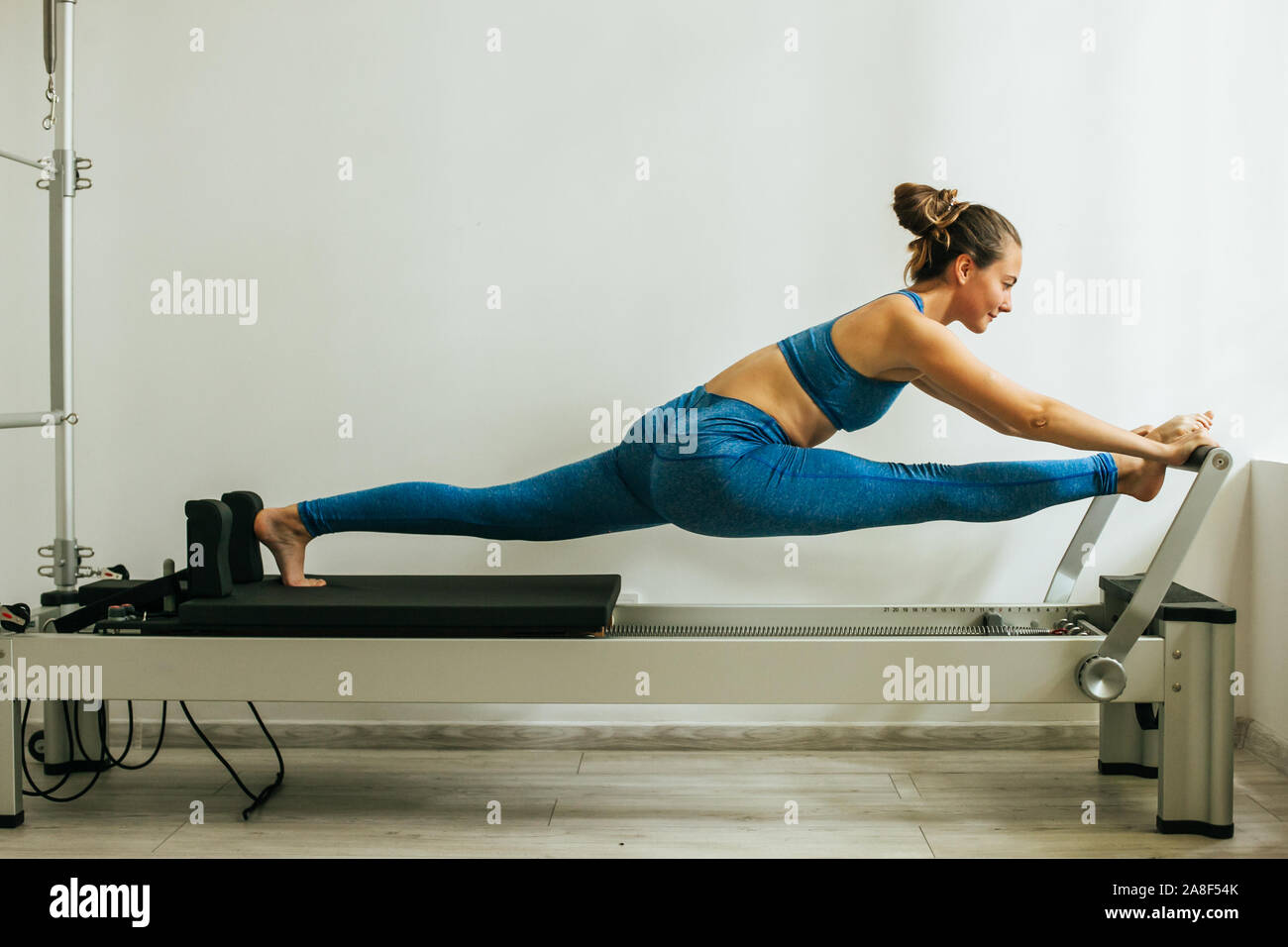 Woman performing Pilates exercise using a Cadillac or Trapeze table Stock Photo