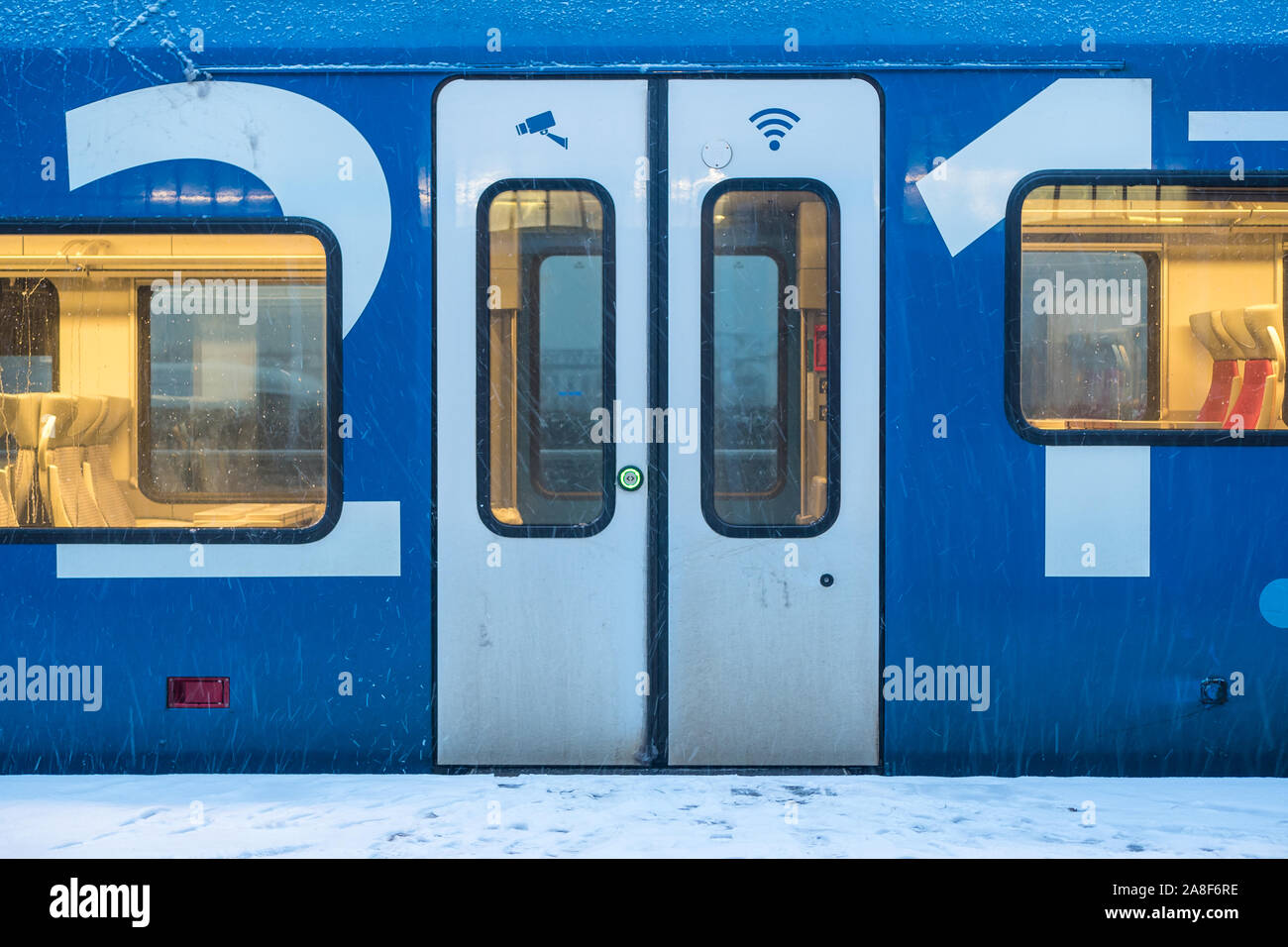 A blue and white Keolis train is weiting for departure. The doors are closed and the interior lights are on. Stock Photo