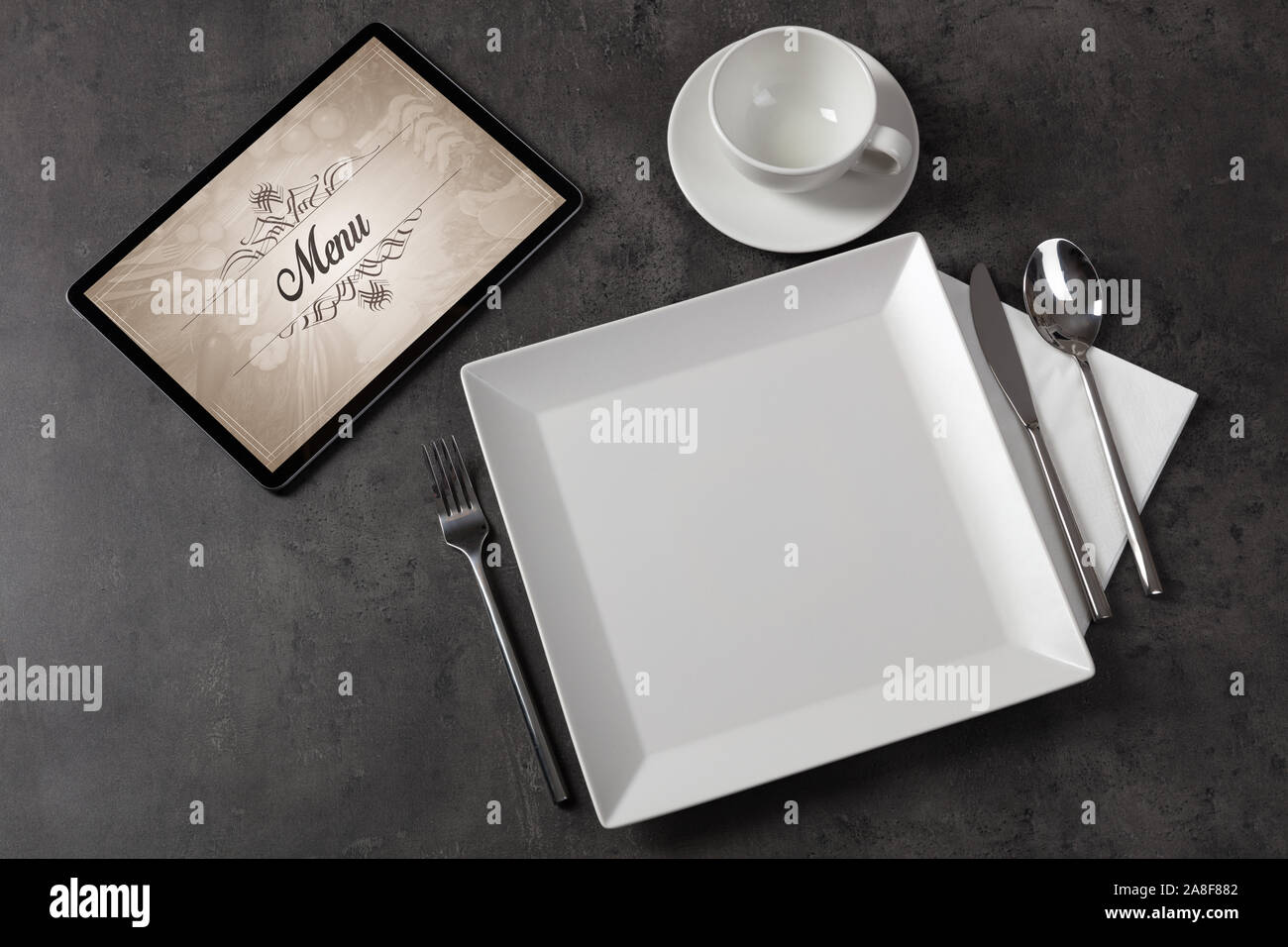 Tablet with stylish restaurant logo and laid table Stock Photo
