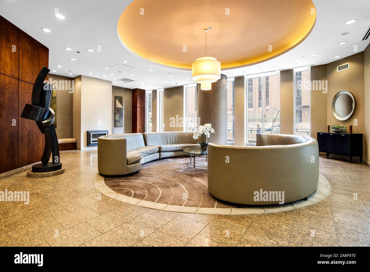 A modern lobby waiting area in a downtown Chicago high rise with a wrap around couch and chandelier hanging down from the ceiling. Stock Photo