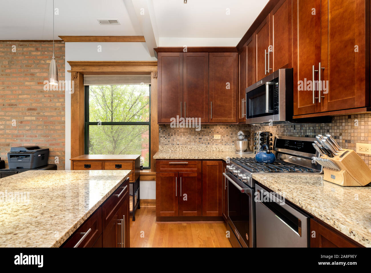 A Chicago condo with exposed brick and dark cabinets in the kitchen with granite and a tiled back splash. Stock Photo