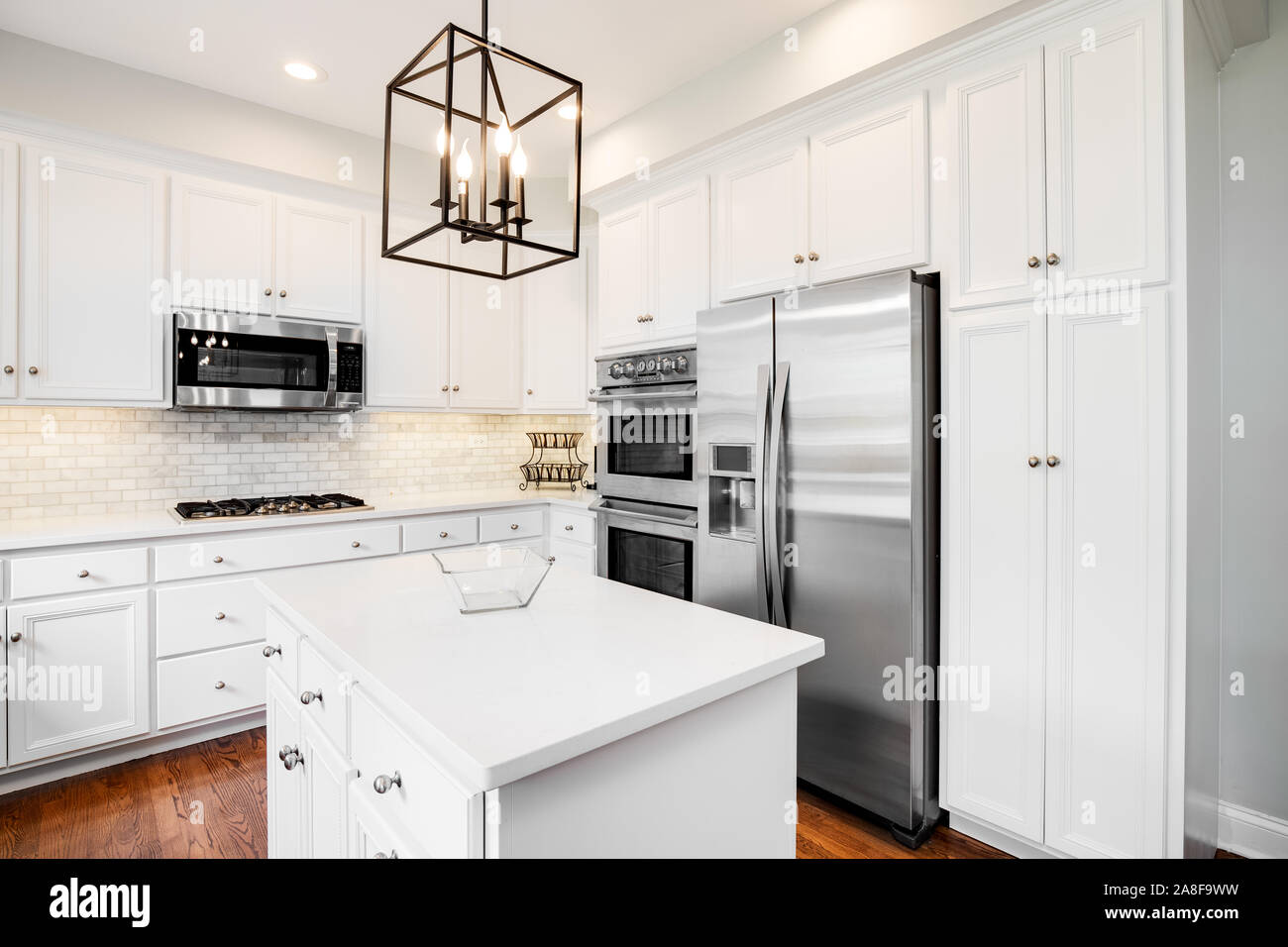 A beautiful kitchen with dark wood cabinets, marble countertops, chairs  sitting at the island, and stainless steel appliances. No brands or names  Stock Photo - Alamy