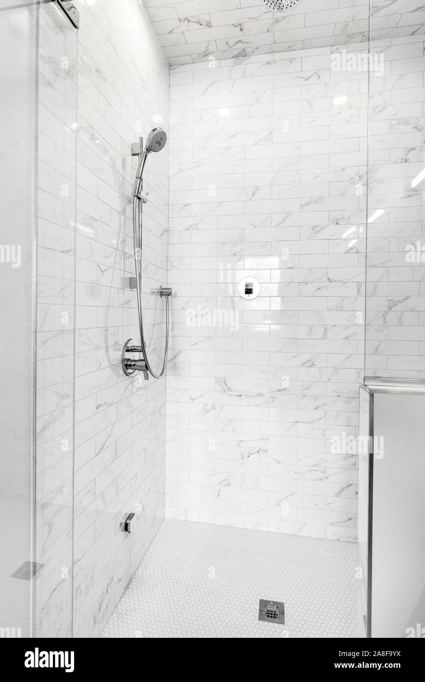 A luxurious, remodeled shower with chrome fixtures and white, marble