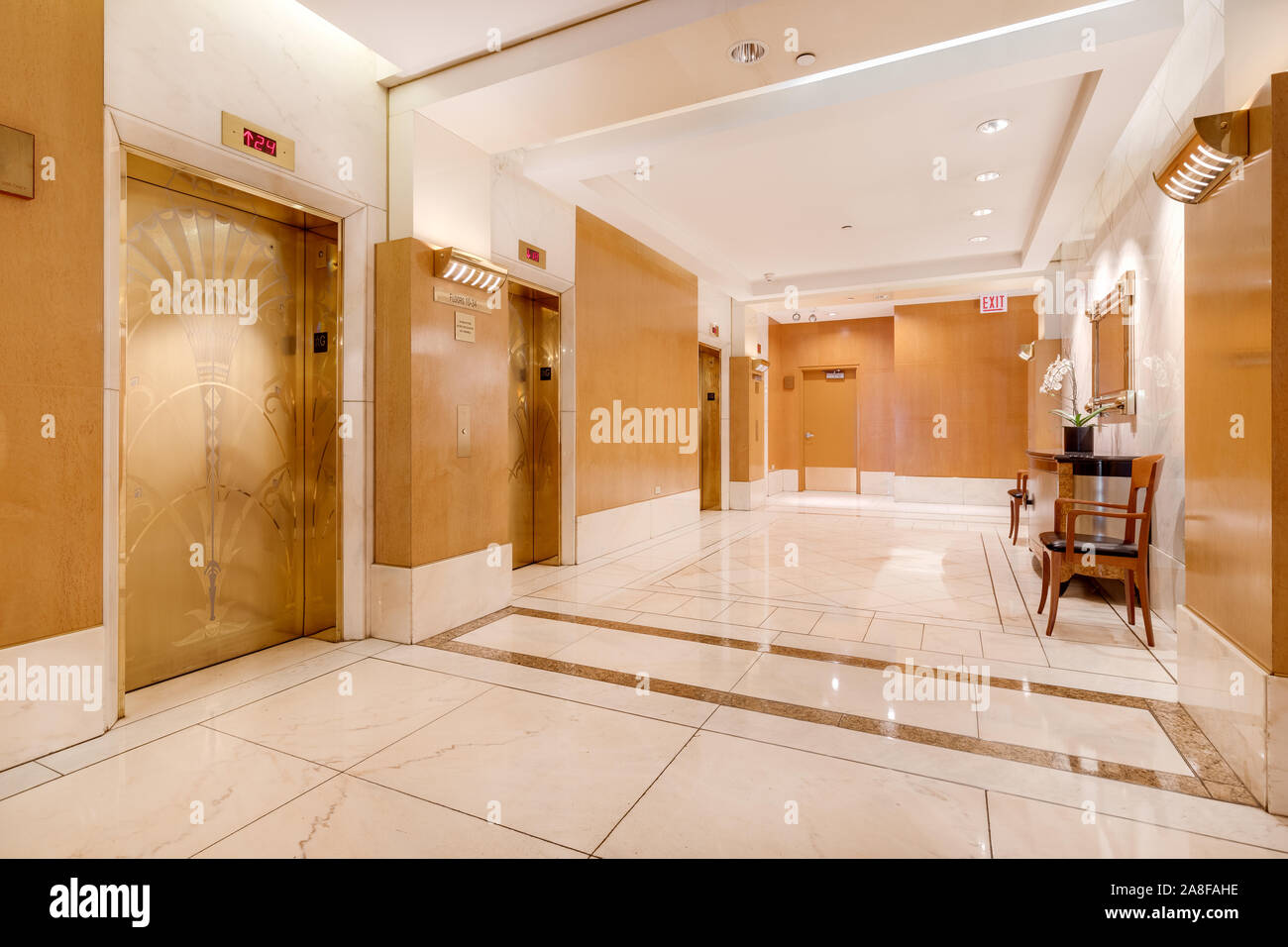 A elevator lobby at an expensive Chicago high rise with gold elevator doors and tiles covering the hallway floor. Stock Photo
