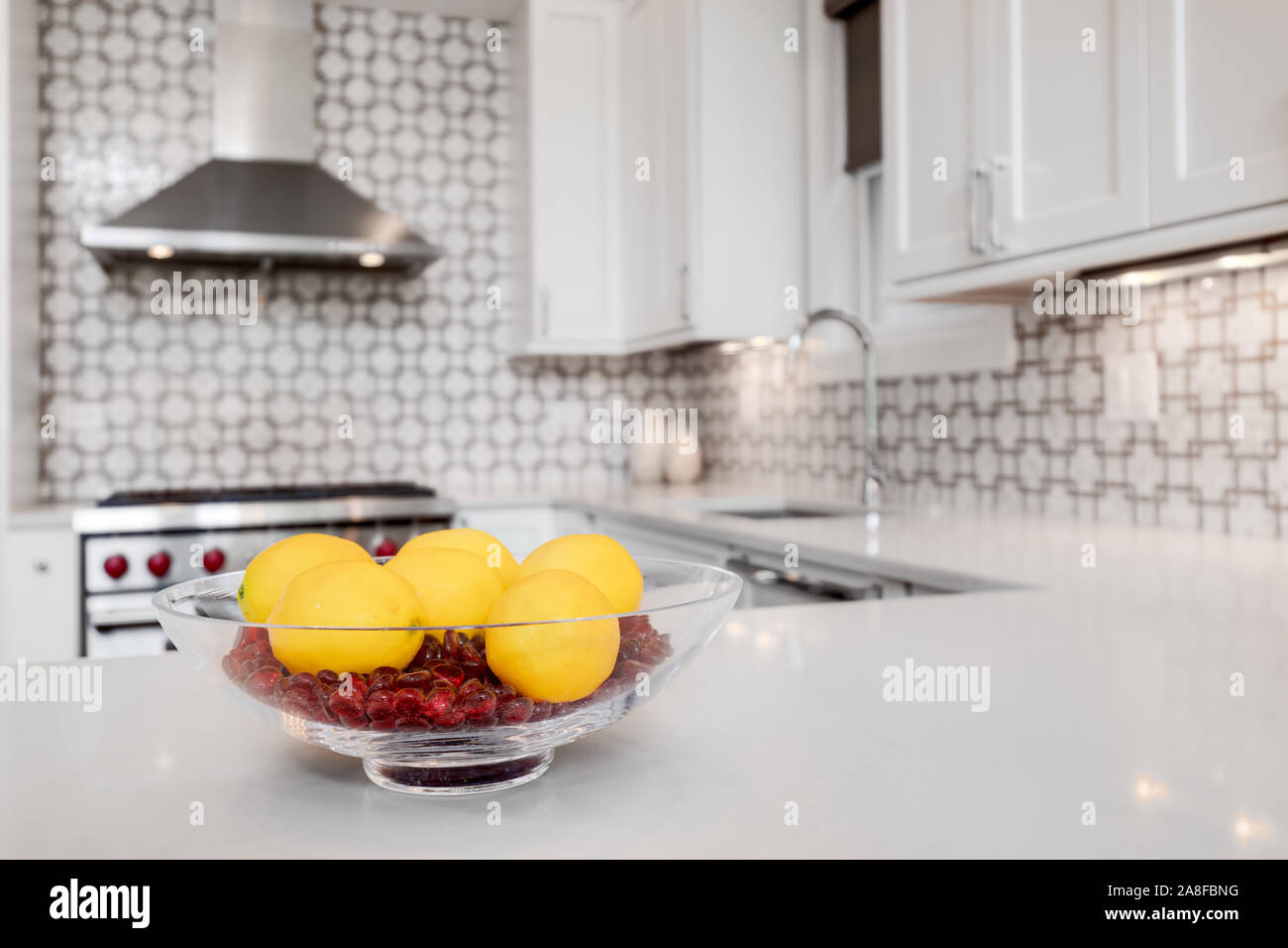 A luxury kitchen with a Wolf oven and hood with a beautiful tiled back splash. The colorful centerpiece with lemons make the colors pop. Stock Photo