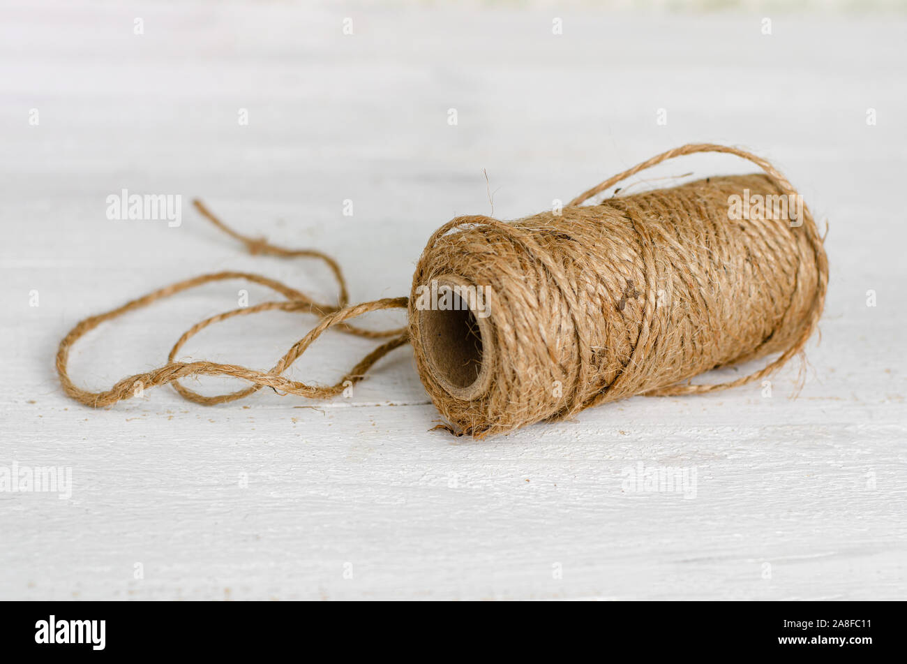 Natural jute twine roll on white wooden background. Tools for