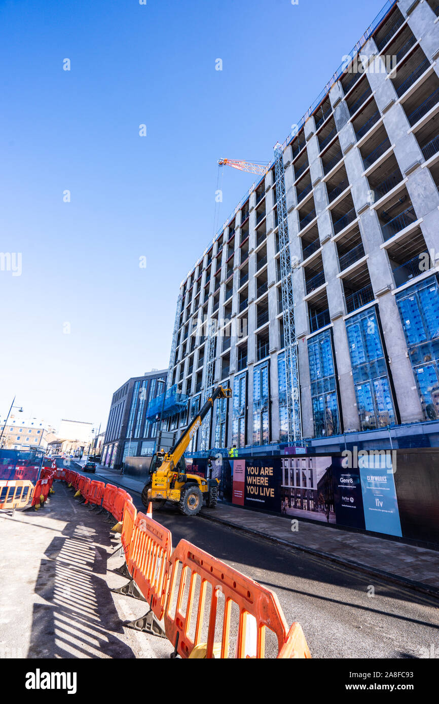 A JCB driver works on the new Hilton Hotel building, structure in Stoke on Trent, Hanley, loading and unloading materials for his work colleagues Stock Photo