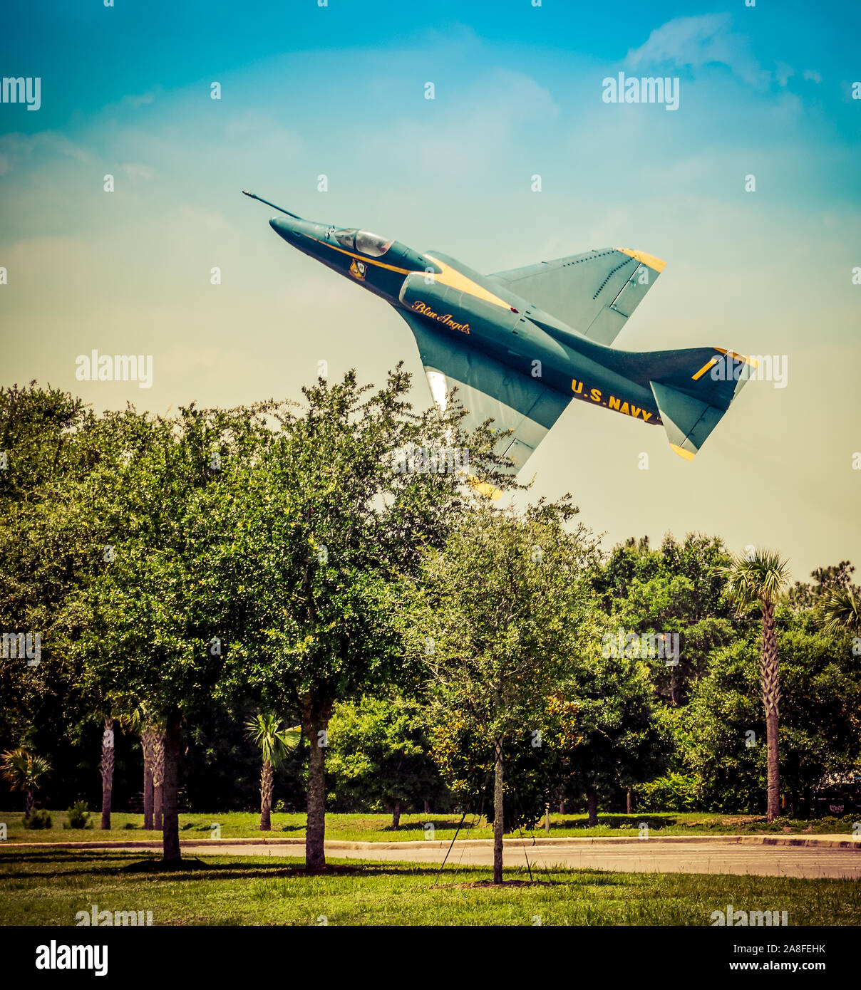 A low flying vintage US Navy Blue Angels airplane banking over treetops in the USA Stock Photo