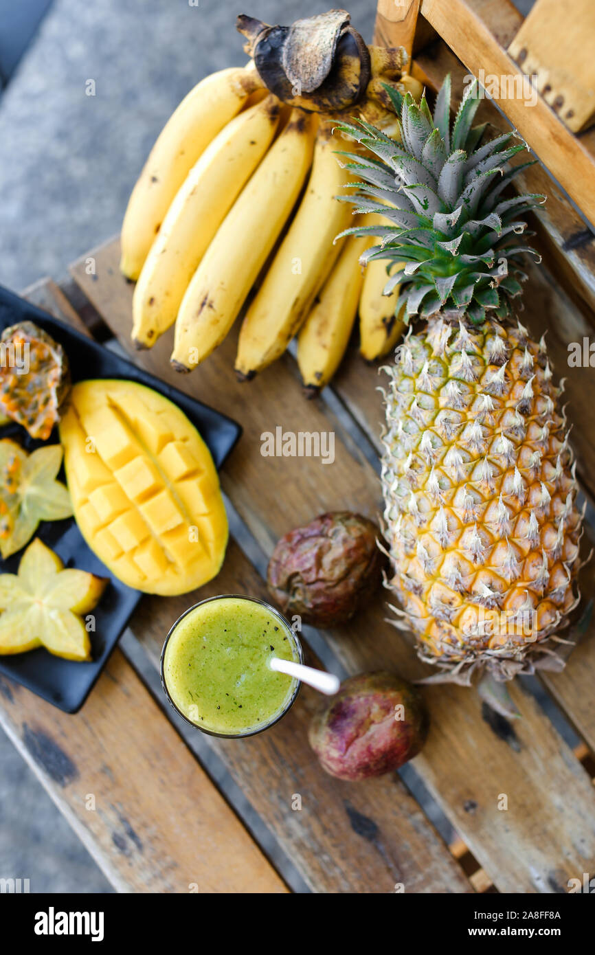 Kiwi fresh green juice near bananas, carambola with mango and pine-apple. Stock Photo