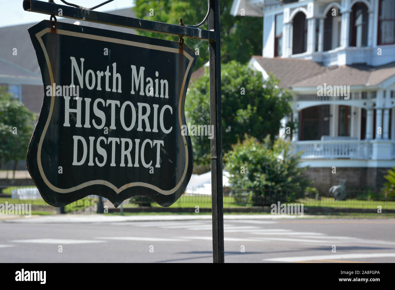 An antique style metal sign reads,  North Main Historic district, placed on the corner near Victorian Houses in Hattiesburg, MS, USA, Stock Photo