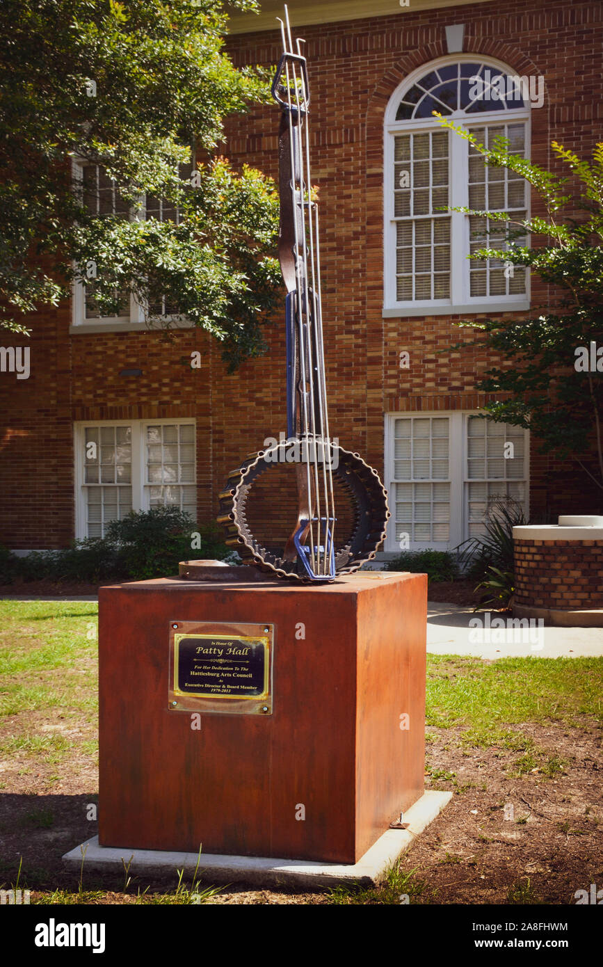 A metal box pillar supports an abstract banjo sculpture made of metal, honoring and memorializing Patty Hall, in  Hattiesburg, MS, Stock Photo