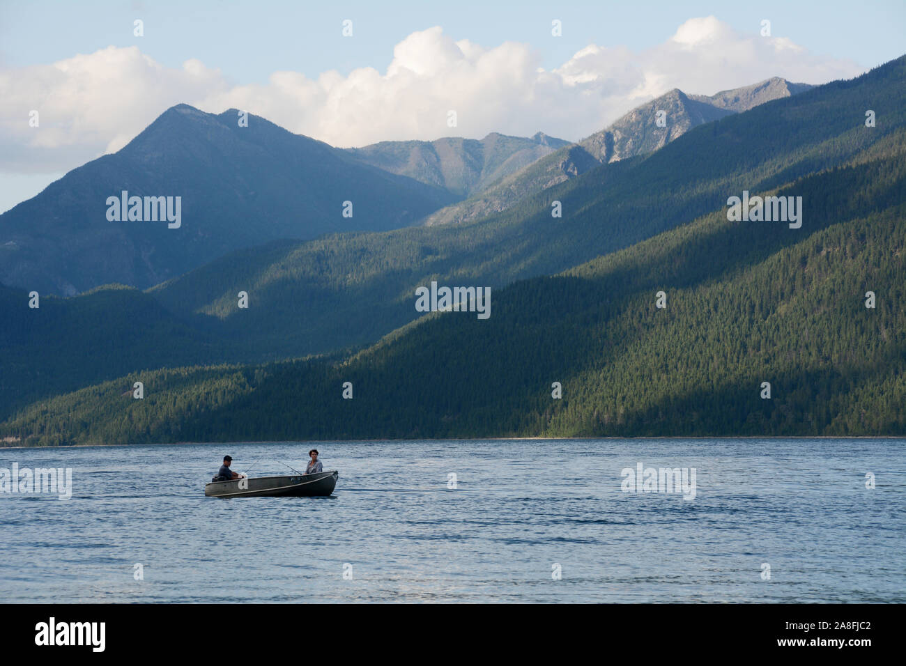 Two people in a motorboat in Kootenay Lake, with the mountains of the Purcell Wilderness Conservancy in the background, British Columbia, Canada. Stock Photo