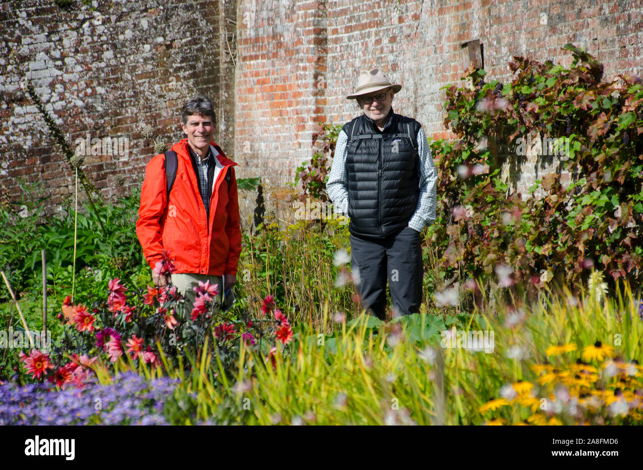 Friends on tour: Two older men wearing hats stand in the blooming flower gardens  at Stourhead gardens, in Wiltshire UK Stock Photo