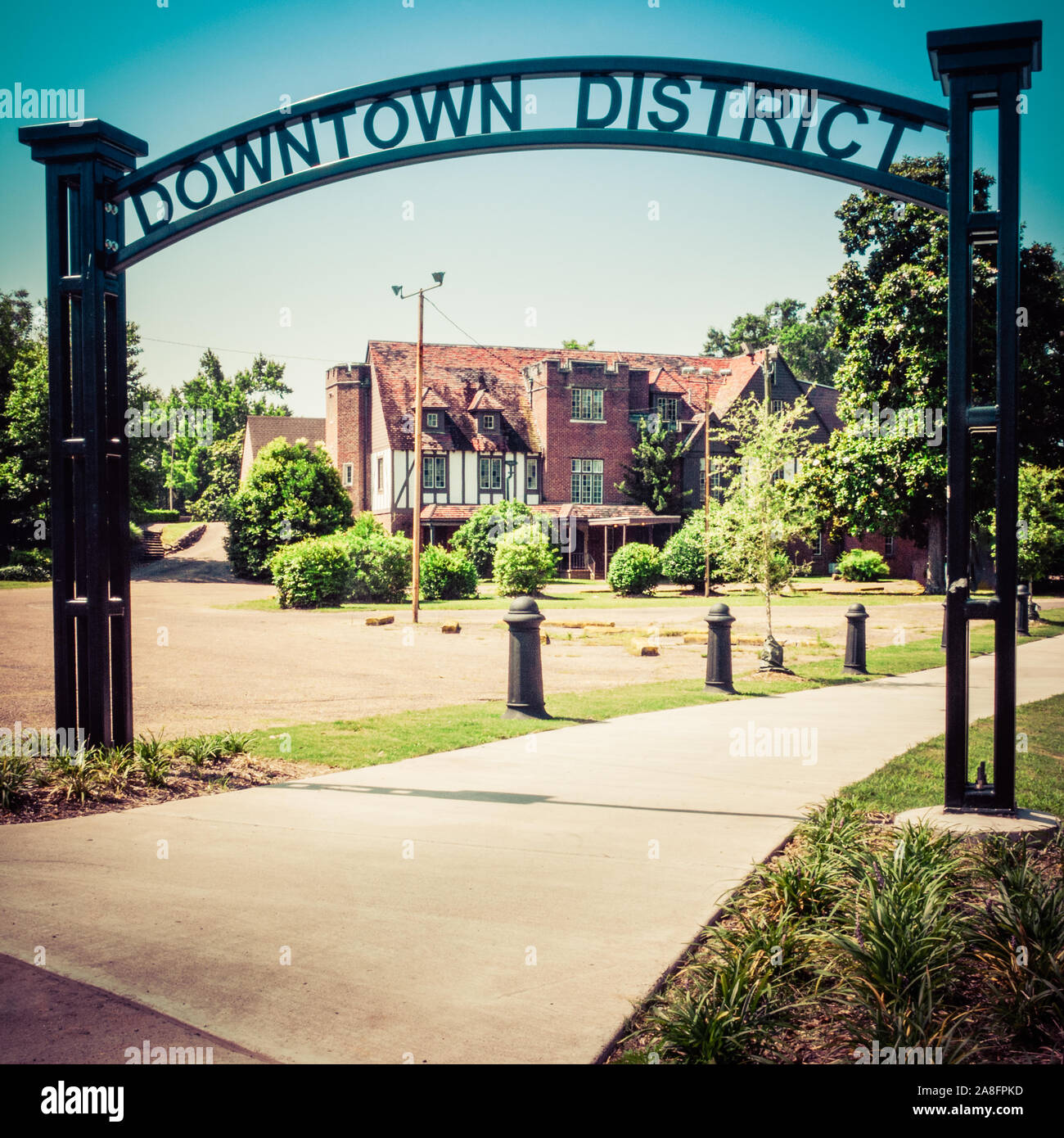 An overhead black metal cutout design sign reading downtown district