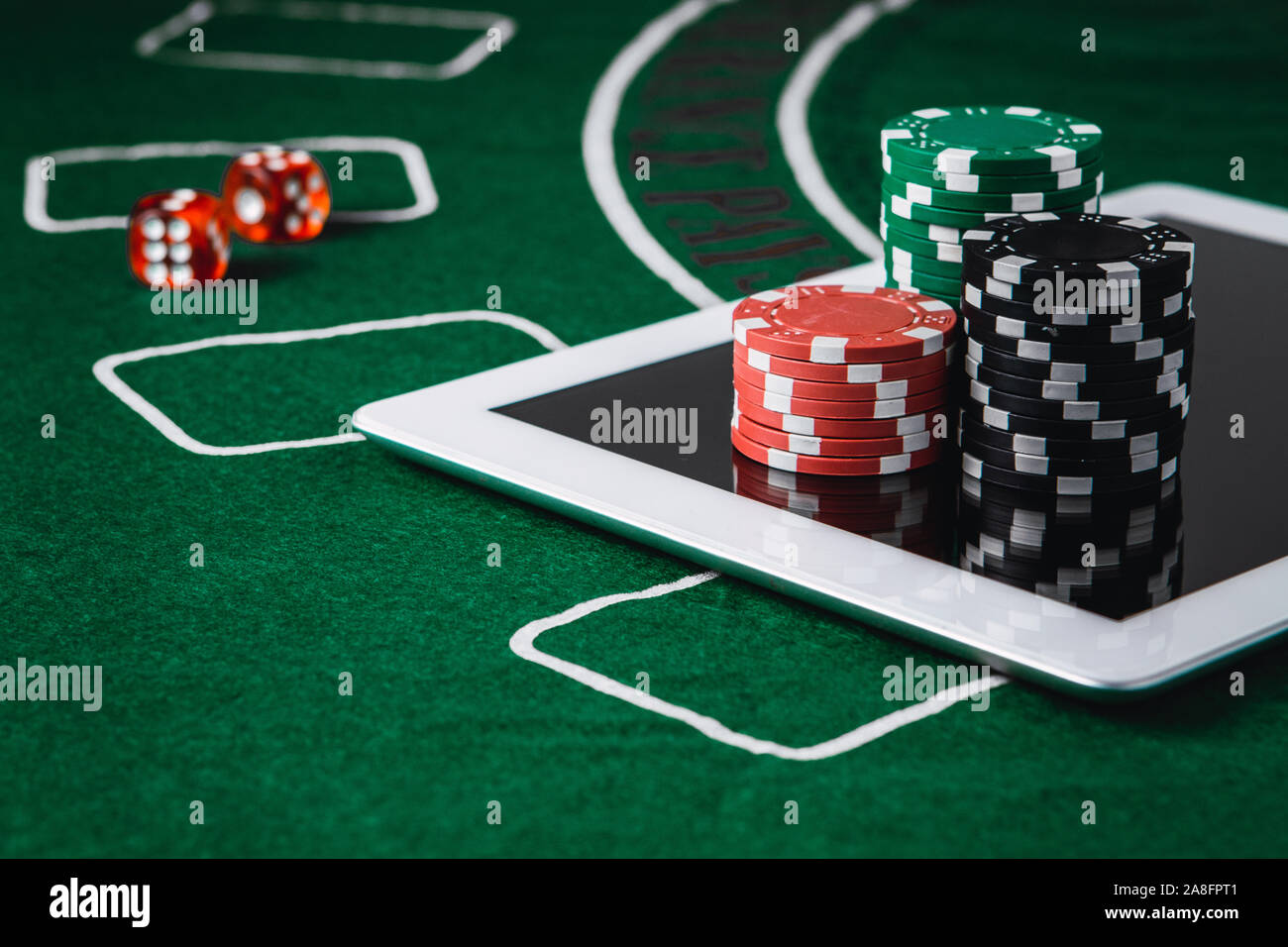 Poker online and gambling concept. Poker chips and a digital table on a green felt Stock Photo