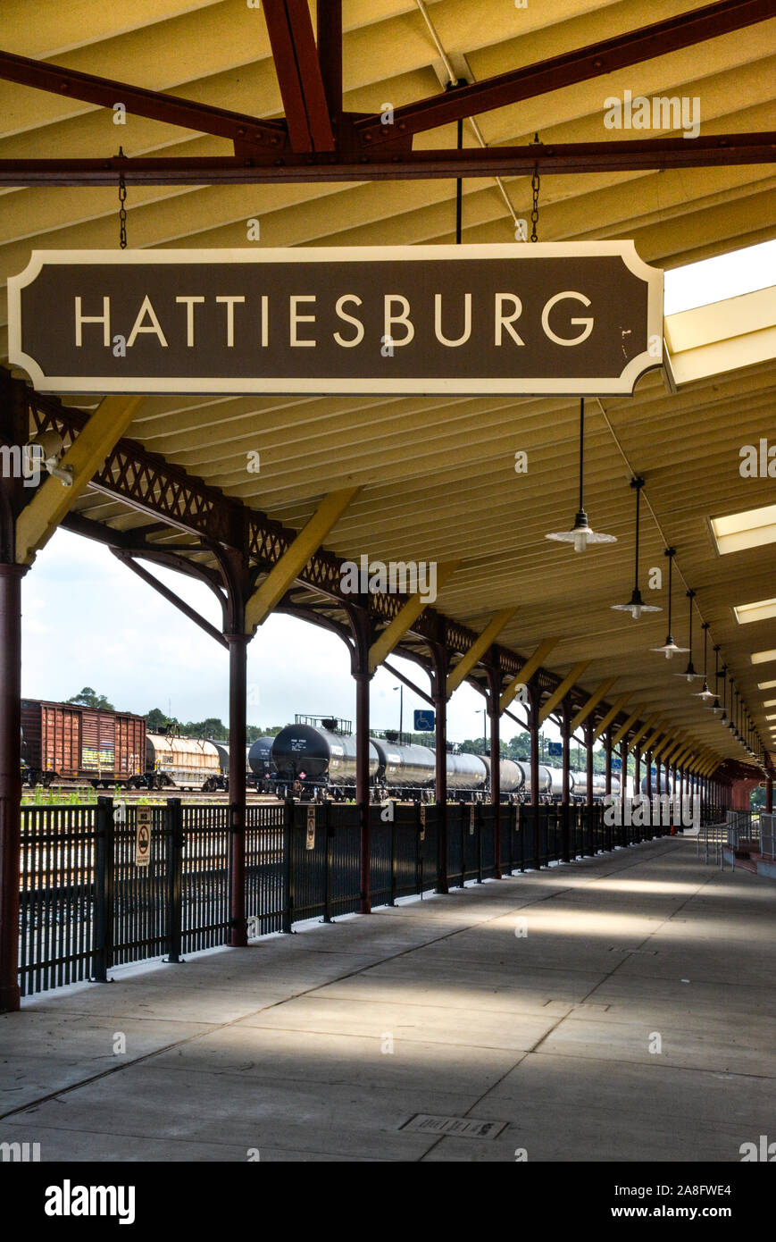 Overhead canopy for Passengers waiting area for boarding at the Hattiesburg, MS, train depot, with nameplate sign and oil tankers nearby, Hattiesburg, Stock Photo