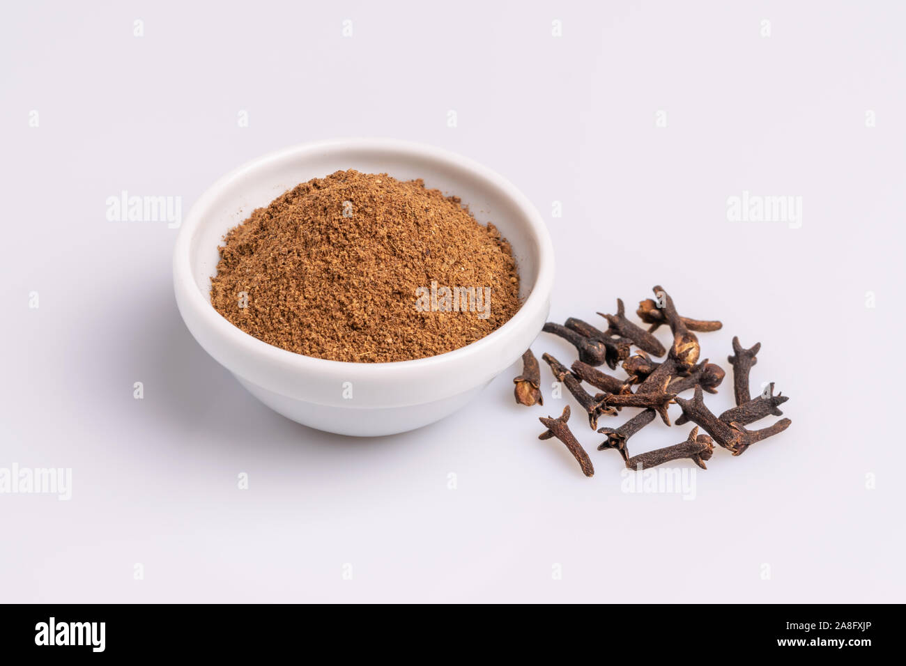Ground cloves in white ceramic bowl isolated on white background, soft