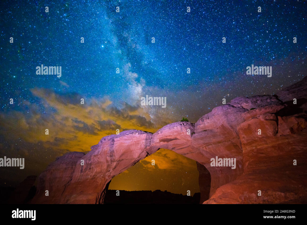 MIlky Way amd clouds lit by Moab, Utah, Broken Arch, Arches National Park, Stock Photo