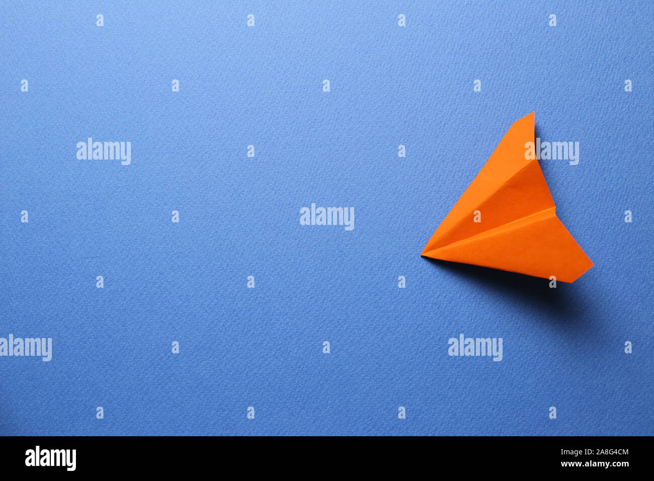 Orange paper plane on blue background Stock Photo