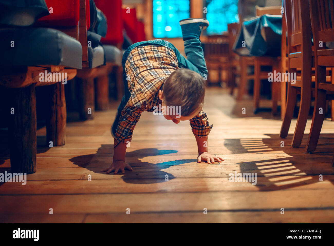 Cute adorable boy three years old having fun in cafe restaurant. Child playing on floor in public place. Freedom of self expression and behaviour for Stock Photo