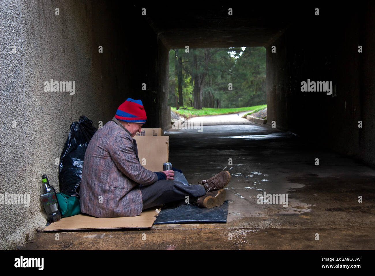 Homeless man shelters from rain in underpass in Canberra, Australia Stock Photo