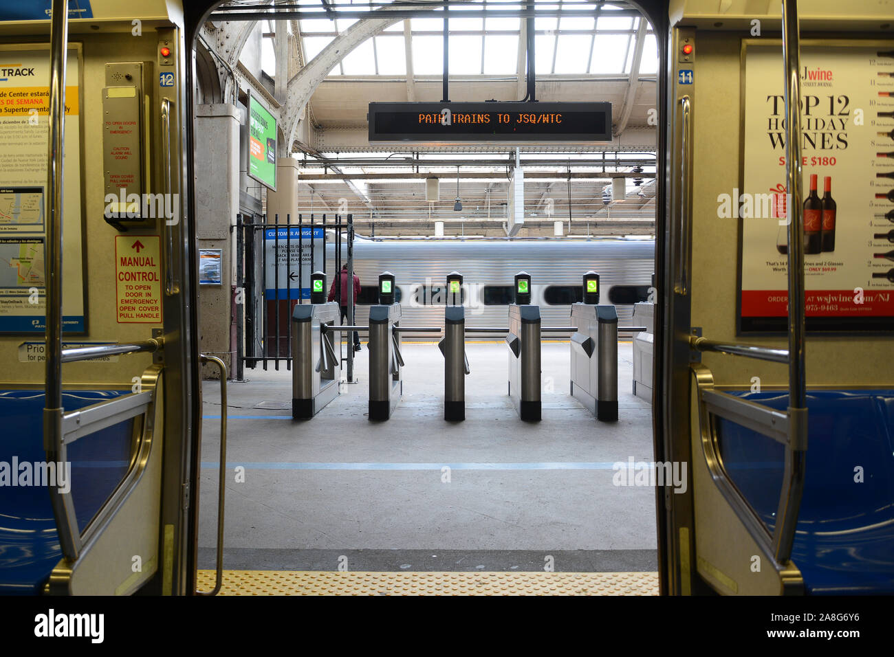 NEWARK, NJ - 05 NOV 2019: View from inside a Path Train with the doors open looking onto the paltform with turnstiles and passing train. Stock Photo