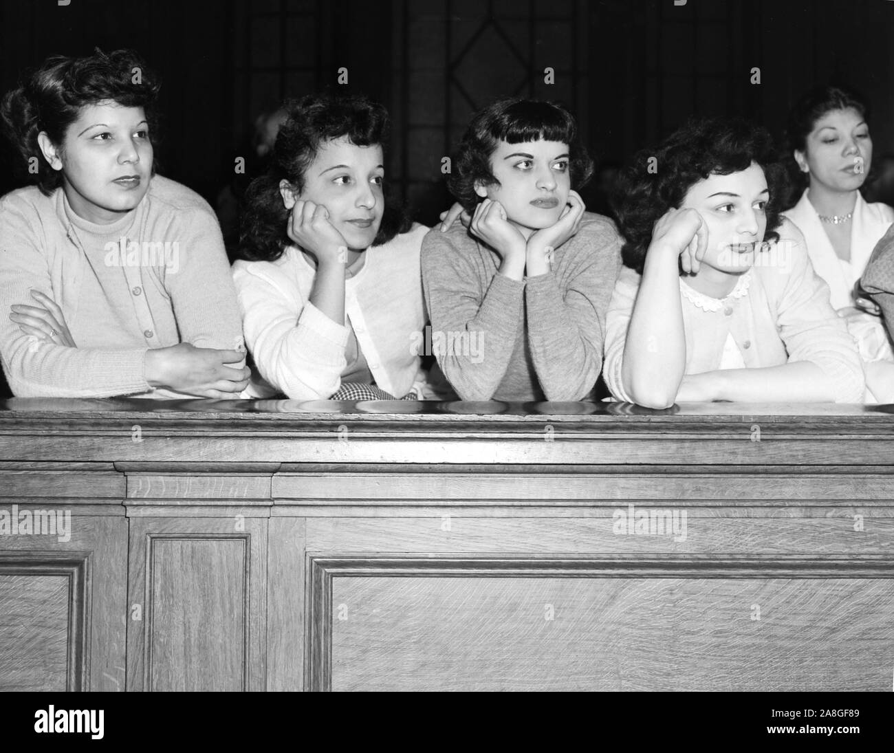 Young women in the front row intensely watch the hearing of Chicago police officer Michael Moretti who was charged with murder in 1951. Stock Photo