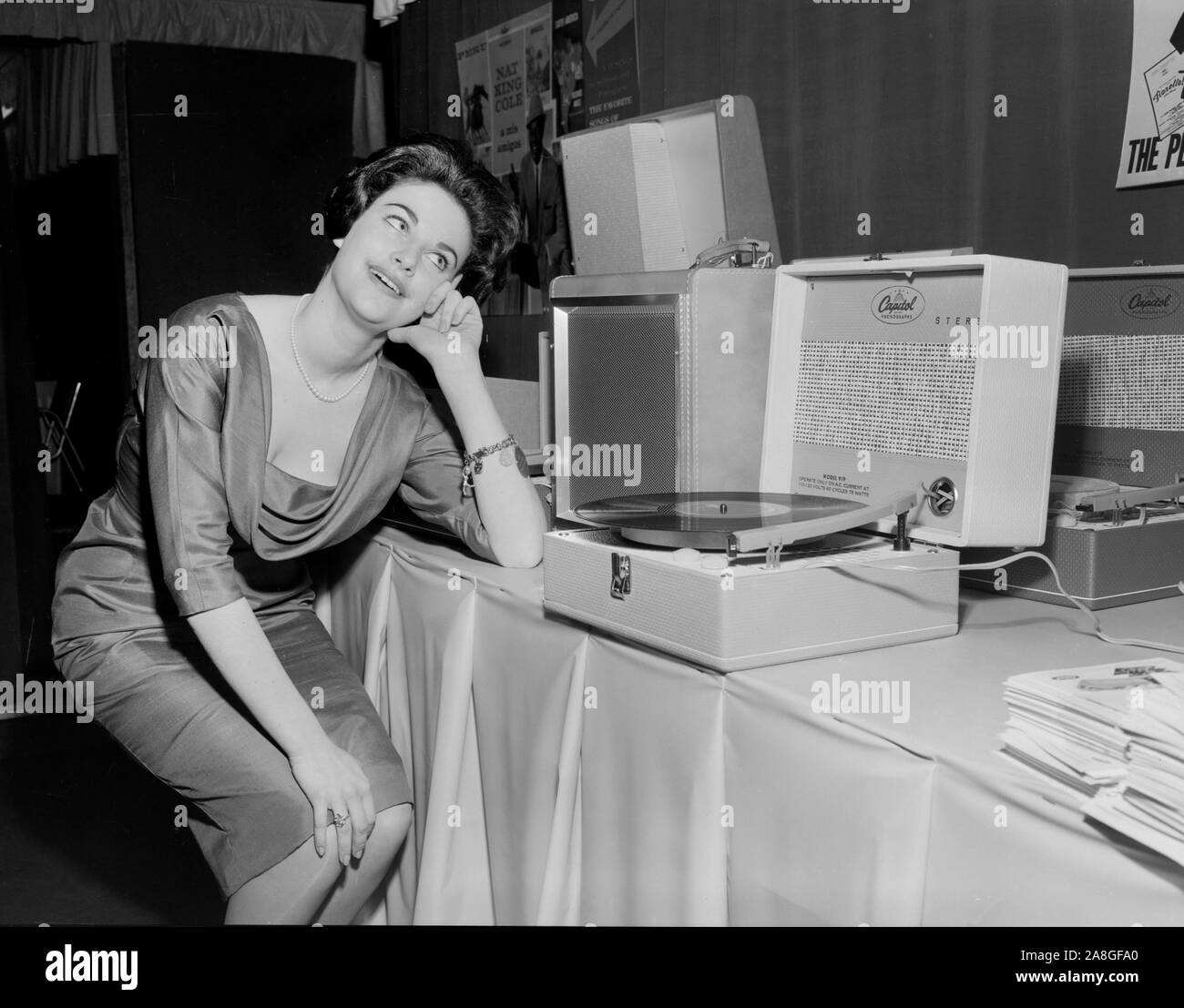 A model playfully listens to a period record player at a retailers convention in Chicago, ca. 1958. Stock Photo