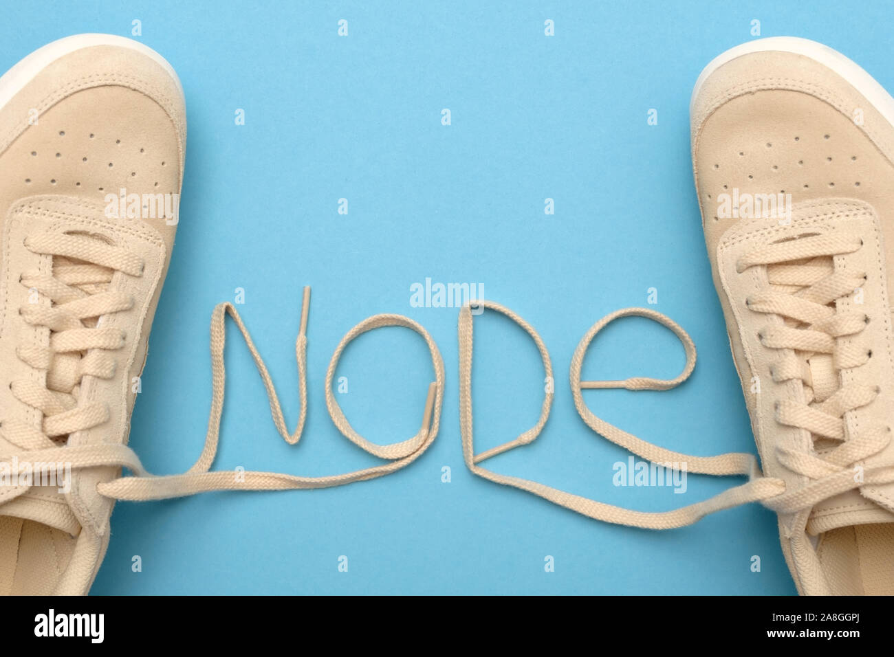 New women sneakers with laces in node text. Flat lay on blue background. Stock Photo