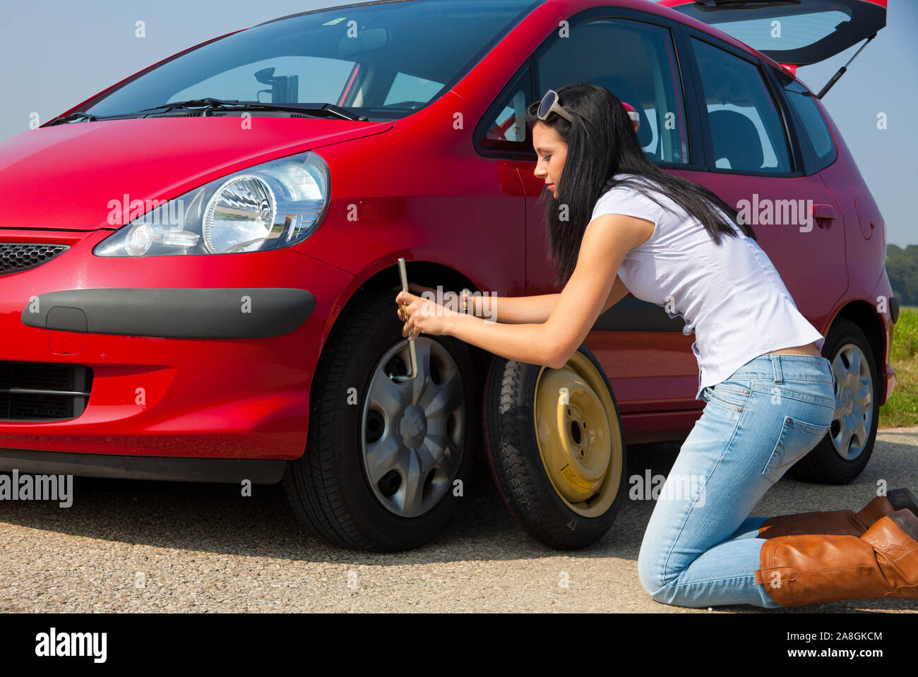 Junge Frau mit einer Reifenpanne am Auto, MR:Yes Stock Photo