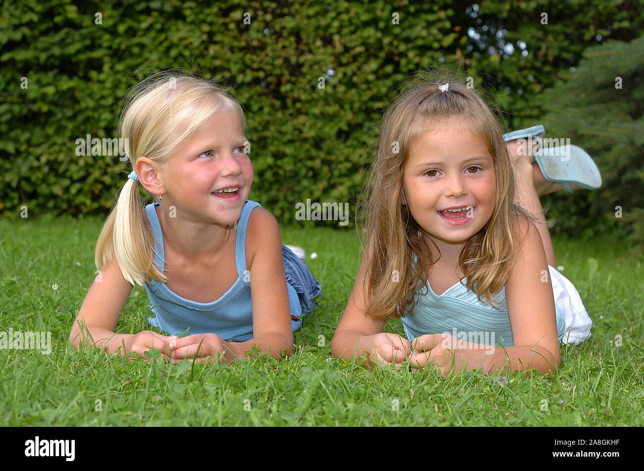 Zwei lachende Kinder liegen im Park auf einer Wiese, Mädchen, 6 Jahre ...
