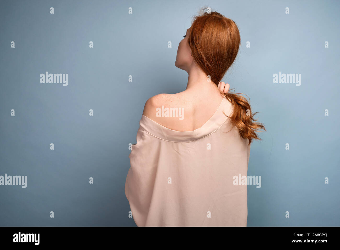 A shot from the back of a red-haired girl in a light robe lowered from ...