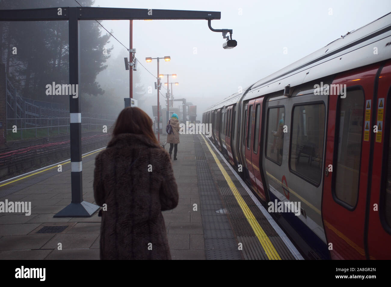 north west London, Harrow on the hill, commuters walking on the tube station platform, catching the tube to work in the tick fog morning. Stock Photo