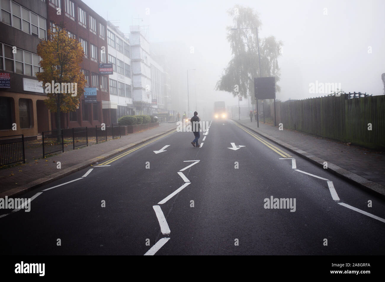 North west London, Harrow on the hill, a man is crossing the road on a very foggy morning Stock Photo
