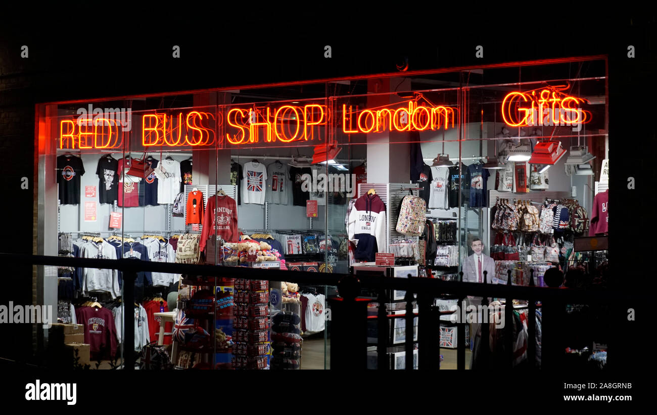 London, United Kingdom - October 4, 2019: Outside of Red Bus Shop London Gifts shop at night with gifts illuminated by shop lights and multiple reflec Stock Photo