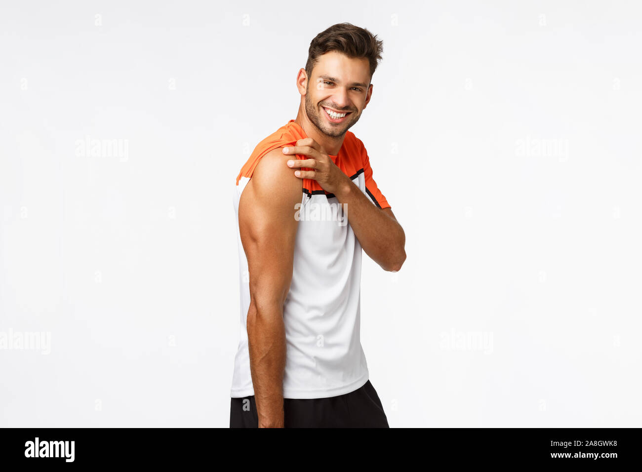 Studio portrait sassy, masculine handsome sportsman in activewear raise t-shirt sleeve and tense muscles, showing strong biceps, good body shape Stock Photo