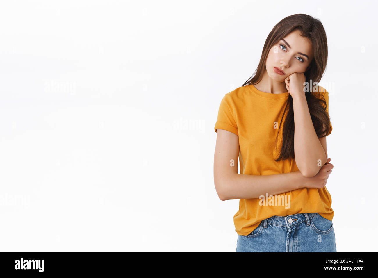 Bored, unamused and reluctant good-looking young stylish woman in yellow t-shirt, facepalm, lean on fist and look with apathy, feeling boredod Stock Photo