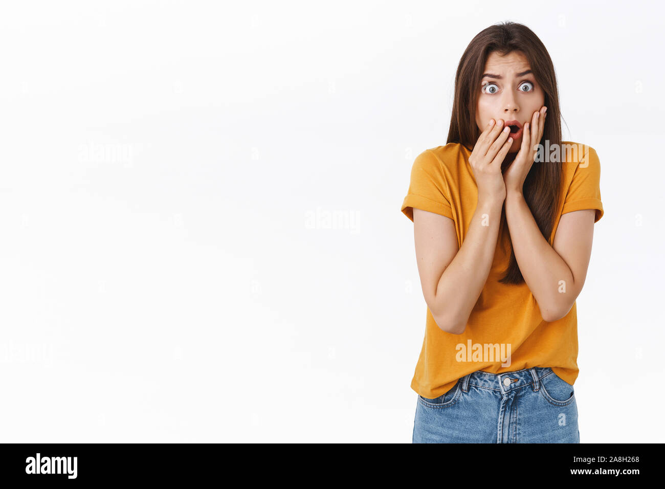 Scared, shocked timid insecure woman standing speechless, drop jaw, gasping stare camera frightened, hear stunning rumours, holding hands on mouth Stock Photo