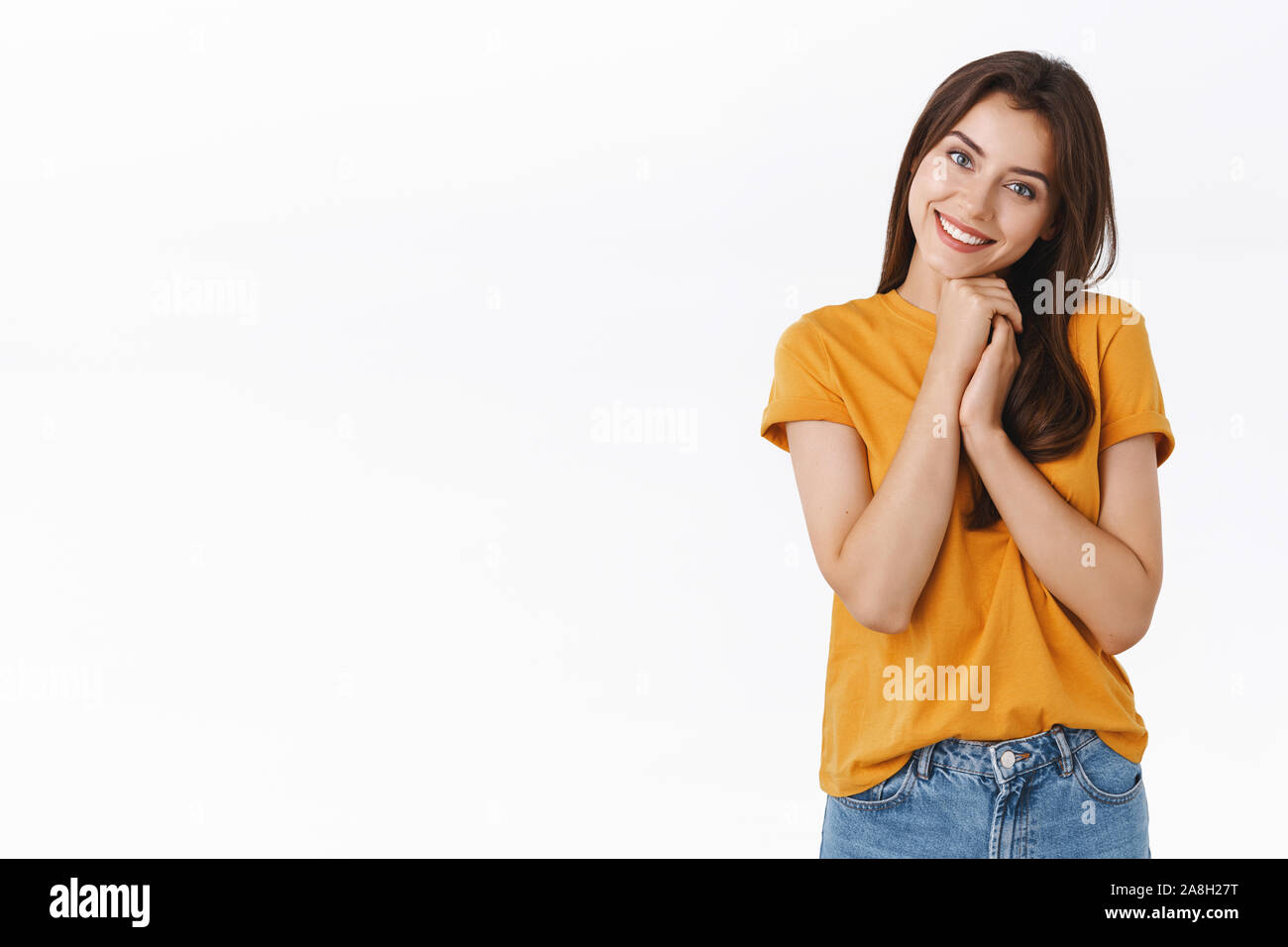 Tender, cute and feminine girl see lovely picture, sighing and smiling gently clasping hands together, tilt head and contempating something touching Stock Photo