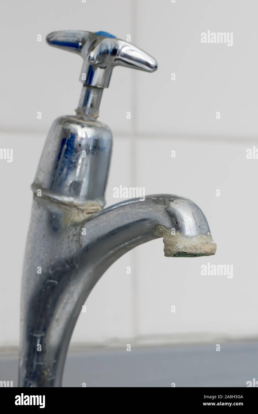 Limescale. Close-up of hard water calcium carbonate deposit on faucet tap. Selective focus close up of lime scale deposit build-up on old kitchen or b Stock Photo