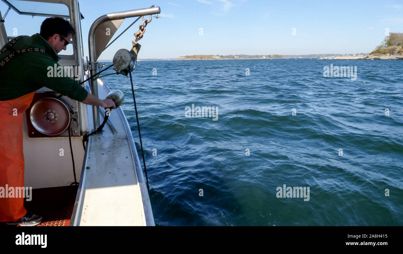 PORTLAND, MAINE, USA - OCTOBER, 19, 2017: a fisherman starts winching in a lobster trap on a boat at portland, maine Stock Photo