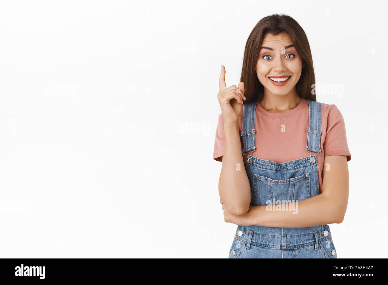 Cute relieved girl finally got excellent idea, sharing her plan or suggestion, smiling happy and silly looking camera, raise one finger in eureka Stock Photo
