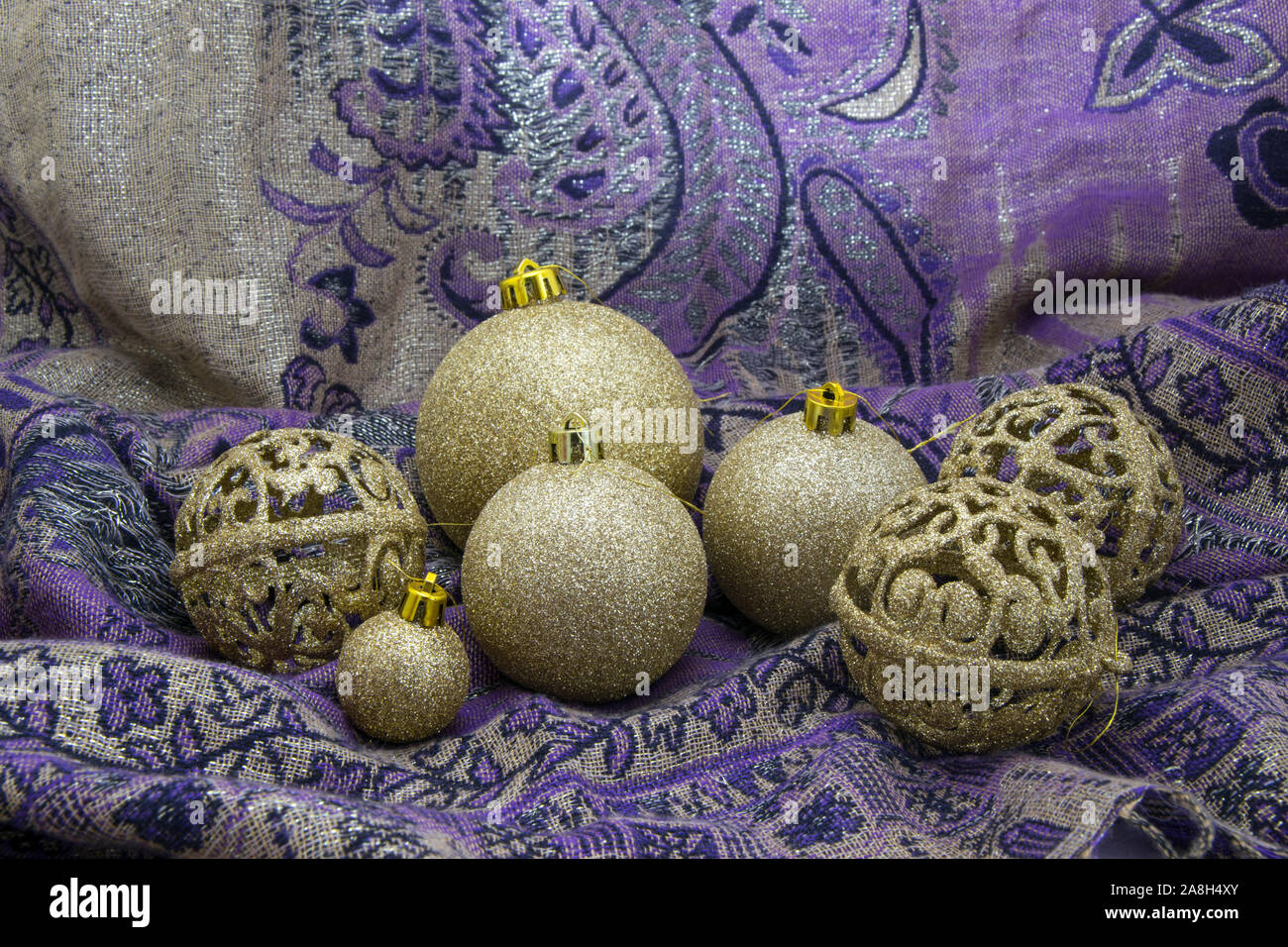 Golden baubles arrangement on purple textile. Stock Photo