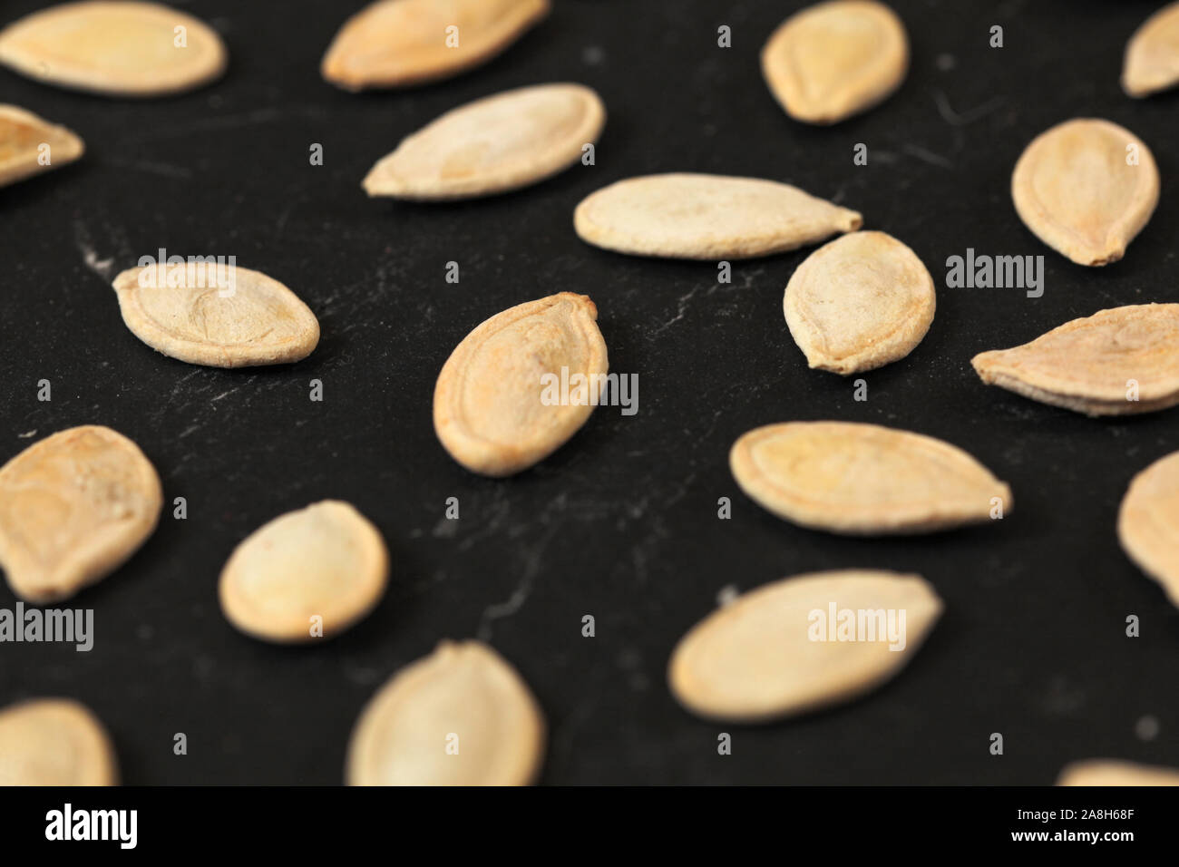 Roasted and salted pumpkin seeds on black board, shallow depth of field photo Stock Photo