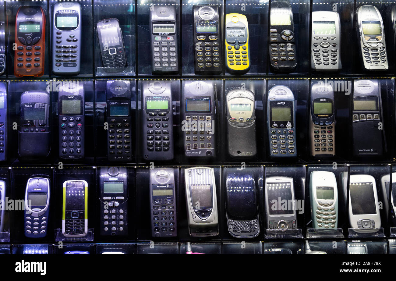 Old mobile phones on a technology market showcase. Cell phones from the early 2000's. Stock Photo