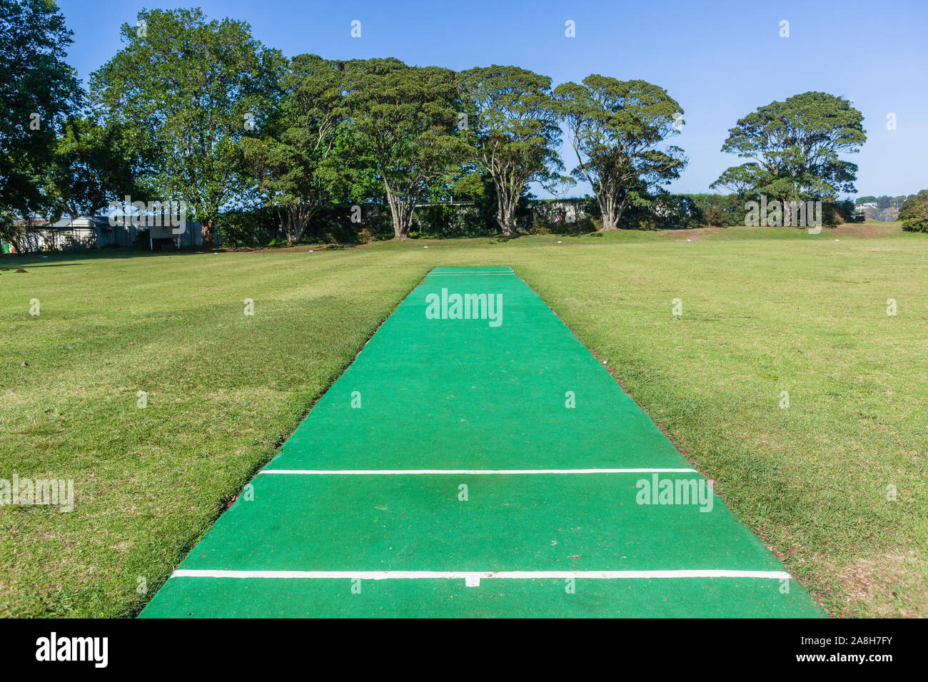Scenic cricket grounds from white boundary fence of grass field astro